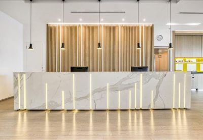 Bright reception area featuring a marble desk with vertical light accents and wood paneling.