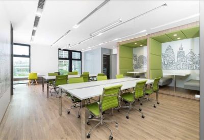 Spacious open-plan coworking area with lime green chairs and illustrated wall murals.