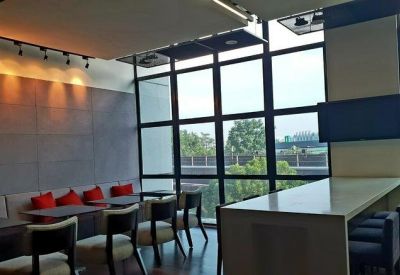 Communal break area with a high white counter, bar stools, and red cushioned bench seating.