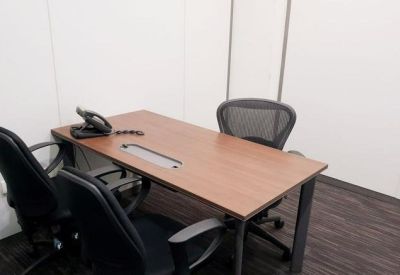 Compact private office with a wooden desk and three black chairs.