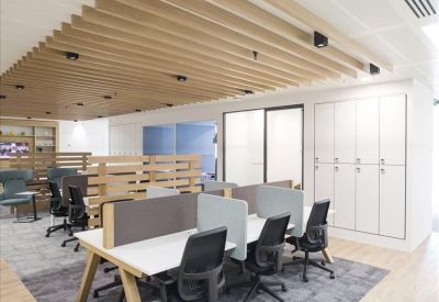Modern open-plan office with light wood slat ceiling and grey privacy dividers.