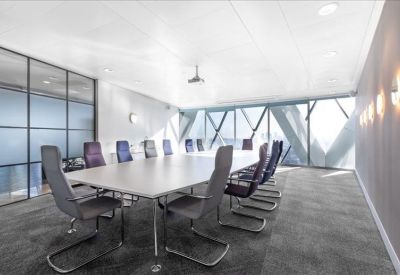 Contemporary glass-walled boardroom with a long white table and ergonomic grey chairs.