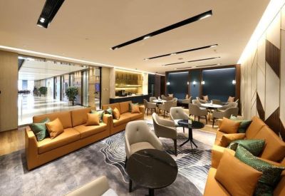 Bright coworking lounge with tan leather sofas and geometric wall art.