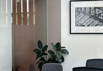 Meeting room with a white table, grey chairs, and framed artwork.