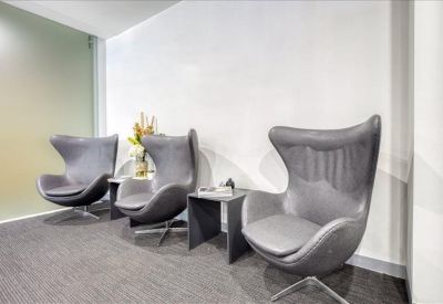 Cozy waiting area with three grey wingback chairs and a frosted glass wall.