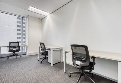 Private office suite with three desks and views of a neighboring skyscraper.