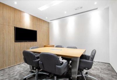 Six-person meeting room with light wood table and black leather chairs.