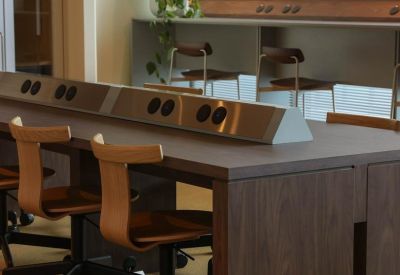 Wooden shared workstation with integrated power outlets and ergonomic chairs.