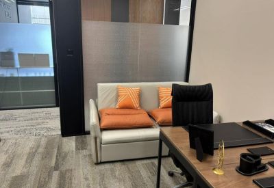 Private executive office with a small grey sofa and orange decorative pillows.