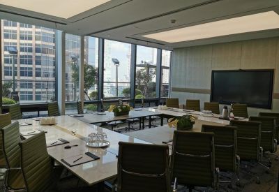 Executive boardroom with a U-shaped marble table and green ergonomic chairs.