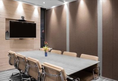 Professional meeting room with a large wooden table, leather chairs, and a wall-mounted screen.