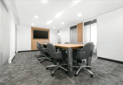 Professional meeting room featuring a long wooden table, grey executive chairs, and a wall-mounted TV.