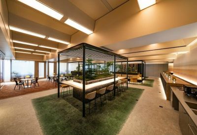 Spacious coworking lounge with a central planter and wooden ceiling beams.