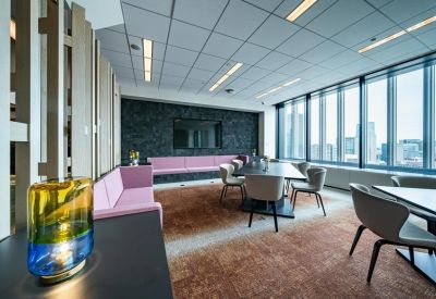 Contemporary meeting room with pink sofas, a dark feature wall, and city views.