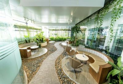 Spacious communal garden lounge with curved seating and indoor pebble paths.