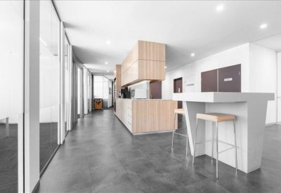 Modern breakout area featuring a white high-top table with wooden stools and timber cabinetry.