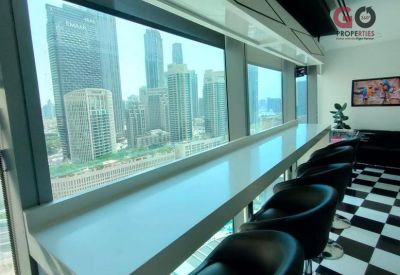 Modern coworking space with a long window-facing counter, black chairs, and city views.