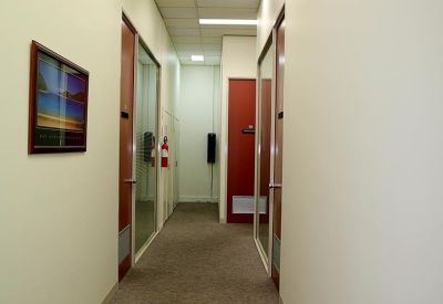 Long office corridor with white walls, red doors, and a small framed picture.