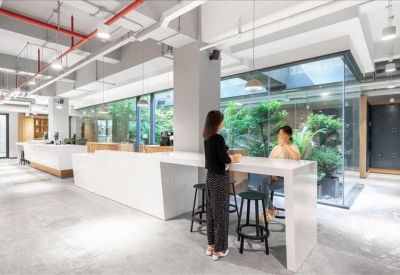 Bright workspace featuring a white counter height table and views of an indoor garden area.