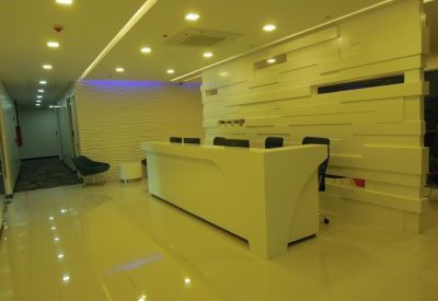 Brightly lit reception area with a sleek white front desk and textured feature wall.