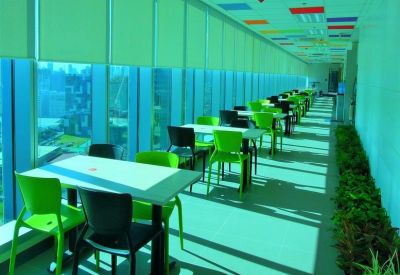Long cafe-style breakout area with bright green chairs and panoramic city views.