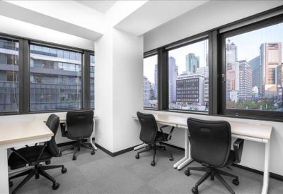 Bright corner office space with four black chairs and large windows overlooking the city.