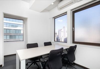 Minimalist meeting room with a white table, black chairs, and frosted glass windows.