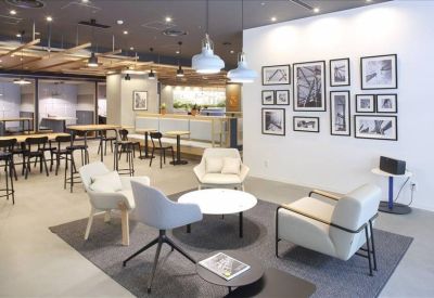 Contemporary lounge area with white armchairs, a gray rug, and a gallery wall.