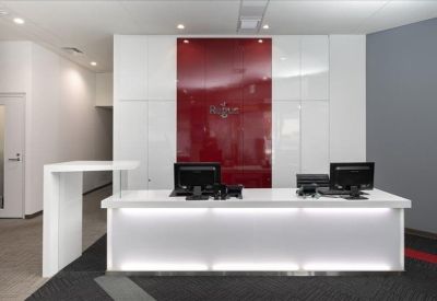 Bright reception desk with integrated lighting and a striking red glass backsplash.