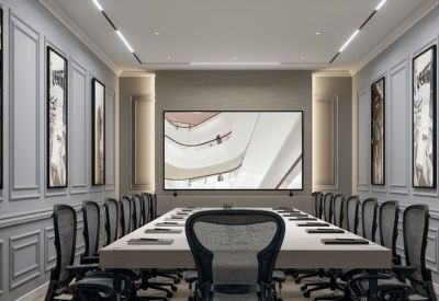 Professional boardroom with a long white table and ergonomic mesh chairs.