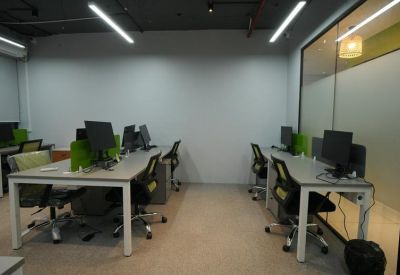 Multiple rows of workstations featuring light wood-toned desks and glass partition walls.