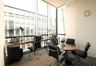 Sunlit private office with workstations and a round meeting table overlooking the city.