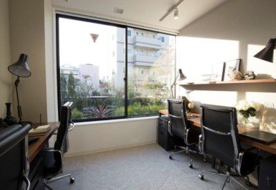 Private office suite with dark desks and large window overlooking the city.