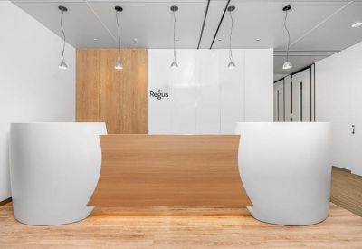Modern reception desk with natural wood paneling and white curved counters.