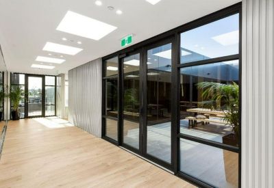 Modern lobby hallway with wood-look flooring and large glass doors leading to a courtyard.