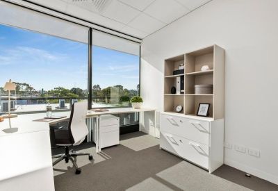 Bright corner office with an L-shaped white desk and panoramic window views.