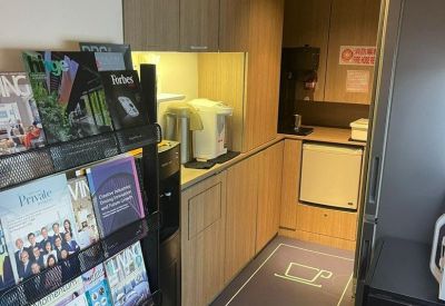 Office kitchen area with light wood cabinetry and a magazine rack.