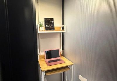 Private office pod with a wooden desk, white modern chair, and frosted glass partition.