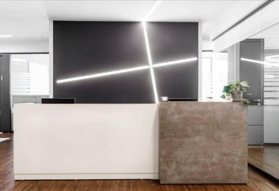 Modern reception desk with a dark feature wall and striking geometric lighting.