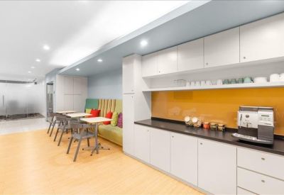 Communal kitchen area featuring a yellow backsplash, coffee machine, and striped booth seating.