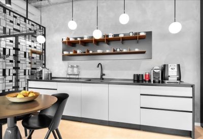 Modern communal kitchen area with white cabinetry, black countertops, and hanging globe lights.