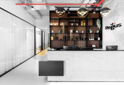 Bright reception area featuring a white desk, wooden shelving, and branded signage.