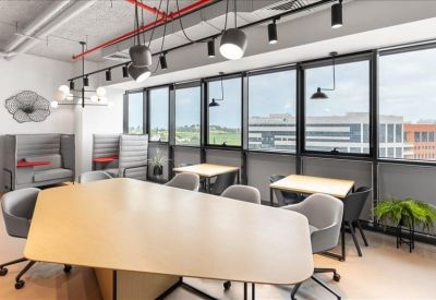 Spacious coworking area featuring a large geometric wood table and panoramic windows.