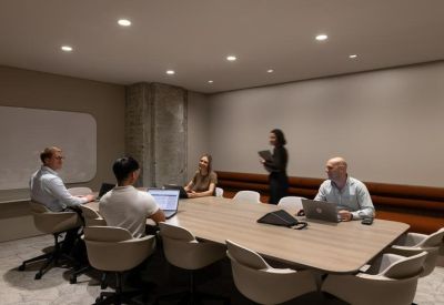 Contemporary meeting room with a large wooden table, grey chairs, and integrated technology.