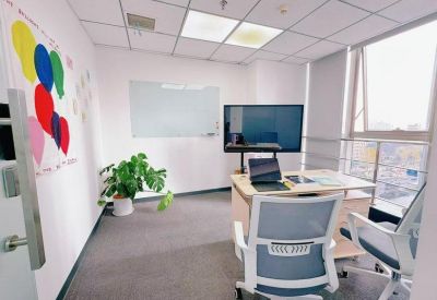 Bright private office featuring a colorful balloon wall mural, large monitor, and floor-to-ceiling windows.
