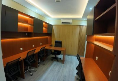 Shared office space with wood desks and built-in shelving with warm backlighting.
