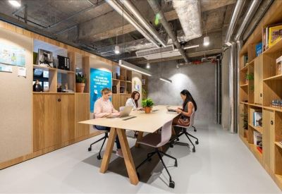 Industrial-style communal workspace with wooden shelving and a long shared table.