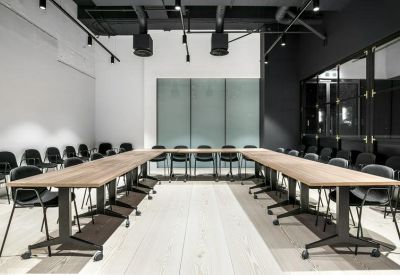 Flexible meeting room arranged in a U-shape with light wood tables and black chairs.