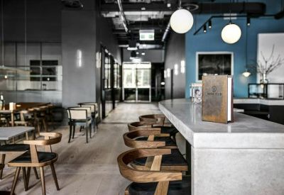 Sleek cafe area featuring a long stone counter, wooden chairs, and a blue accent wall.