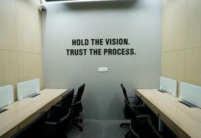 Workspace with long wooden desks and motivational wall text.